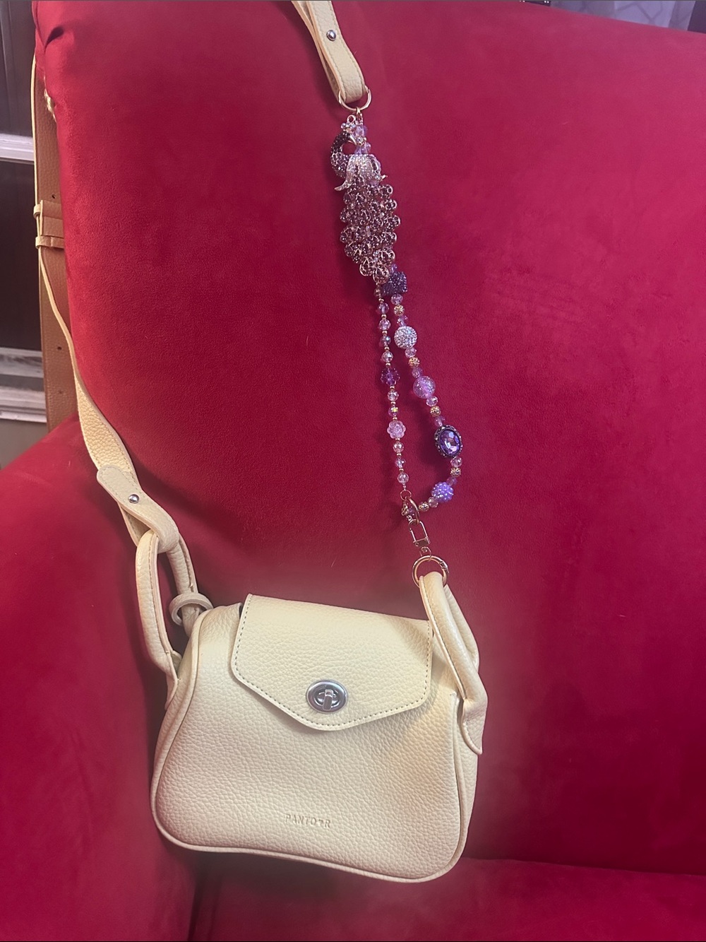 Soft yellow crossbody handbag with charm extension perfect for any occasion